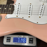Pink electric guitar on a digital scale displaying weight.