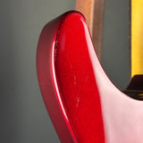 Close-up of the glossy red body edge of an electric guitar, showing a high-shine finish and minor surface scratches against a dark gray background.