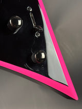 Close-up of a metallic object with pink and silver accents on a gray background