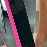 Close-up of a guitar with a pink border held by a person.