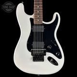 White electric guitar with a black pickguard on a black background, featuring the Tone Shop logo.