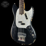 A black electric bass guitar with a distressed finish, featuring a white marbled pickguard and gold hardware, shown against a solid black background with a Tone Shop logo in the top left corner.