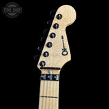 Close-up of a guitar headstock with brand logo on a black background