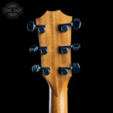 Close-up of the headstock of a six-string acoustic guitar, showing the natural wood grain and six black tuning pegs against a solid black background. A 'TONE SHOP' watermark is visible in the top left corner.