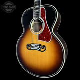 Acoustic guitar with a sunburst finish on a black background, featuring the Tone Shop logo.
