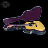 Acoustic guitar in an open case with 'Tone Shop' logo in the corner.