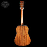 Back view of a wooden acoustic guitar on a black background with 'Tone Shop' logo.