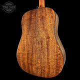 Close-up of a wooden acoustic guitar body with 'Tone Shop' branding.