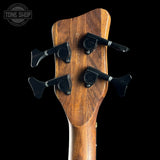 Close-up of a wooden guitar headstock with tuning pegs on a black background, featuring the Tone Shop logo.