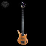 Electric bass guitar with a wood finish on a black background, featuring the 'Tone Shop' logo.