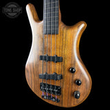 Wooden electric bass guitar with a black background, featuring the Tone Shop logo.