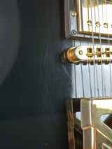 Close-up of a guitar's bridge and tuning pegs on a dark surface