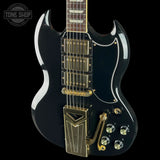Black electric guitar with gold hardware on a black background, featuring 'Tone Shop' logo.