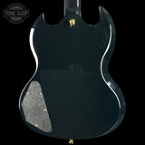 Back view of a black electric guitar with 'Tone Shop' logo.