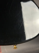 Close-up of a black object with a gold knob on a reflective surface
