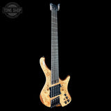 Electric bass guitar with a unique finish on a black background, featuring the Tone Shop logo.