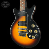 Electric guitar with sunburst finish and black pickguard on a black background, featuring 'Tone Shop' logo.