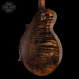 Close-up of a wooden guitar body with a dark finish on a black background, featuring the Tone Shop logo.
