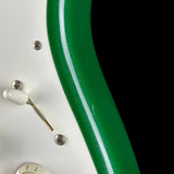 Close-up of a guitar neck with green binding and white truss rod cover.