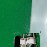 Close-up of a green electronic component with metal contacts on a green and white background