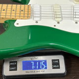 Green electric guitar on a digital scale displaying weight.