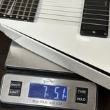 White electric guitar on a digital scale displaying weight