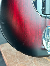 Close-up of a red and black electric guitar on a wooden surface