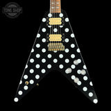 Black electric guitar with white polka dot design on a black background, featuring the Tone Shop logo.