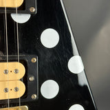 Close-up of a guitar's pickguard with white dots on a black background