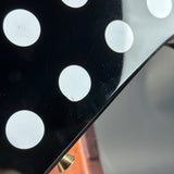 Close-up of a black surface with white circular patterns and a blurred background.