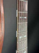 Close-up of a guitar neck with fretboard and wooden fingerboard on a dark background