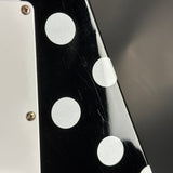 Close-up of a guitar with black finish and white dot inlays on a dark background