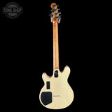 Electric guitar with a natural finish on a black background, featuring the Tone Shop logo.