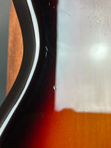 Close-up of a guitar neck with a white pickguard on a wooden surface