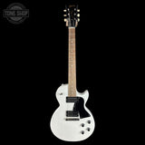 A white Gibson electric guitar with a black pickguard and gold hardware, shown against a solid black background. A 'TONE SHOP' watermark is visible in the top-left corner.