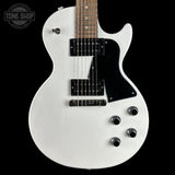 A white electric guitar with a black pickguard and black hardware, shown against a solid black background. A Tone Shop logo is visible in the top-left corner.