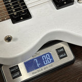 A close-up of a white electric guitar body resting on a digital scale showing a weight of 7.08 lbs.