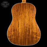 Back view of a wooden acoustic guitar with 'Tone Shop' logo.