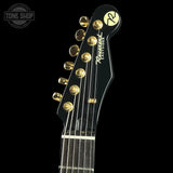 Close-up of a guitar headstock with brand logo on a black background