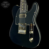 Black electric guitar with gold hardware on a black background, featuring 'Tone Shop' logo.