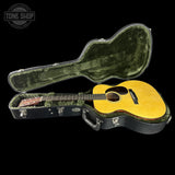 Acoustic guitar in a hard-shell case with 'Tone Shop' logo.