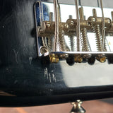 Close-up of a black electric guitar body showing a chrome and gold tremolo bridge with springs and strings.