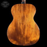 Back view of a wooden acoustic guitar with 'Tone Shop' logo.