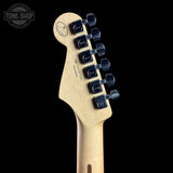 Close-up rear view of a Fender electric guitar headstock in natural maple wood with six black tuning pegs, shown against a black background with a Tone Shop watermark in the top left.