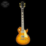 A Les Paul Custom electric guitar in a natural flame maple finish, shown from the front against a solid black background. The guitar features a natural wood grain body, cream pickguard, and gold-toned hardware.
