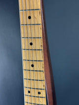 Close-up of a guitar fretboard with frets and strings on a dark background
