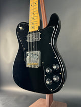 Black electric guitar with a wooden neck on a gray background