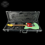Green electric guitar in a black case with 'Tone Shop' logo.