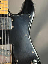 Close-up of a black electric guitar with a blurred gray background