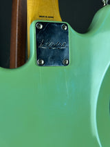 Close-up of a green Fender electric guitar with a visible brand label.